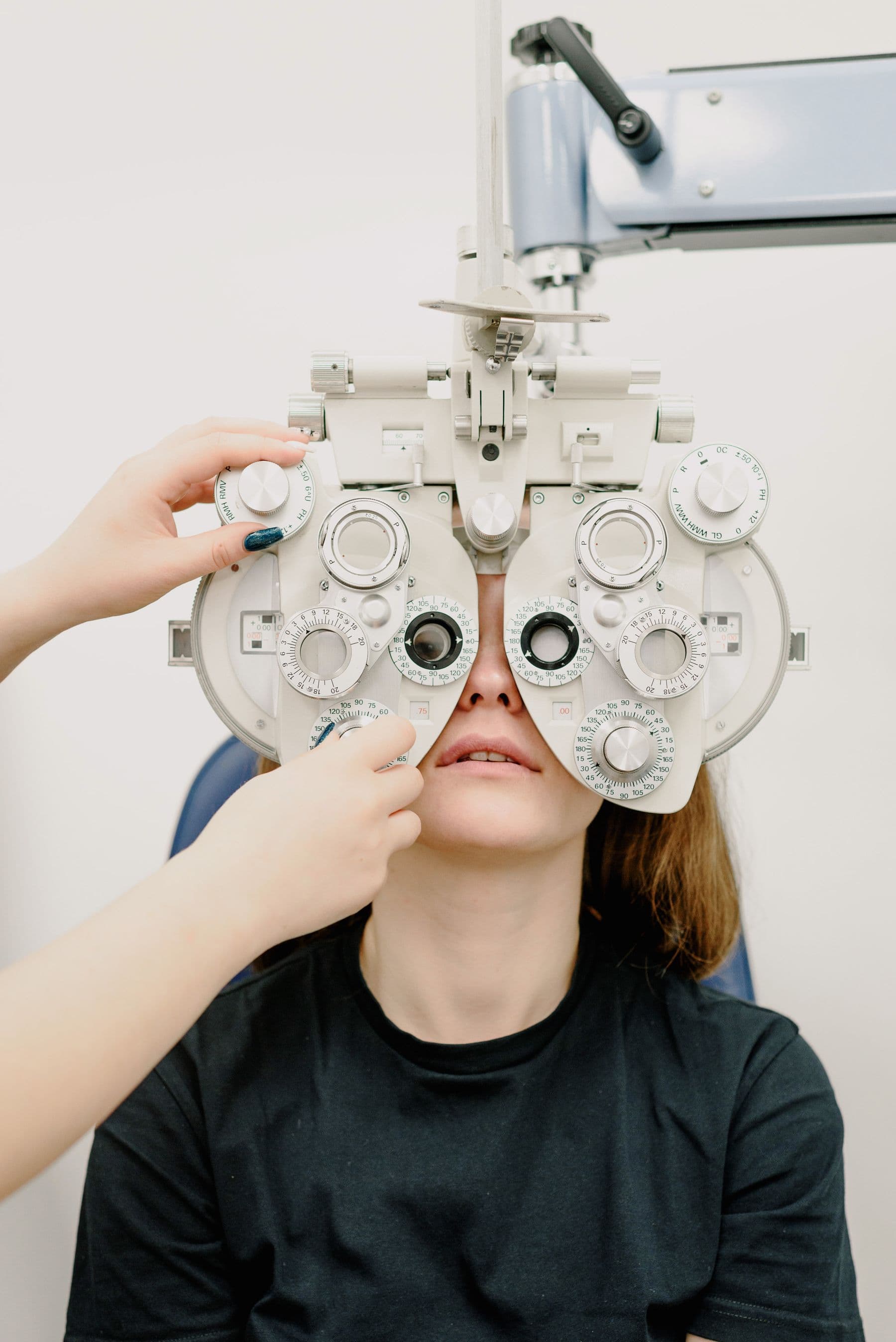 An optometrist adjusting a phoropter during a refraction test